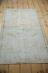 Distressed vintage Oushak rug pile with visible foundation and soft, ghosted floral pattern.