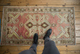 Distressed Oushak rug runner, faded brick red, bronze, and saffron yellow scrolling leaf patterns.