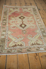 Distressed short pile in faded brick red, pale bronze, and ivory on a vintage Oushak rug.