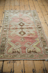 Distressed Oushak rug runner pile with faded raspberry and brown scrolling leaf motifs.
