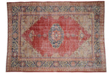 Vintage distressed Oushak carpet with cherry red field, navy floral gul medallion, and geometric borders.
