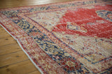 Distressed cherry red and navy blue Oushak rug with visible foundation wear.