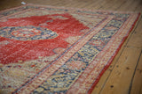 Distressed vintage Oushak carpet's cherry red field, foundation wear, and navy geometric patterns.