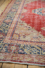 Distressed Oushak rug with cherry red field and intricate navy, beige border detail.
