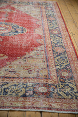 Distressed cherry red field showing wear, with geometric navy blue and beige border patterns.