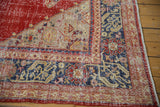 Distressed Vintage Oushak corner: cherry red field, geometric navy blue border, showing even wear.