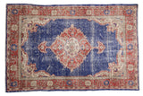 Vintage distressed Oushak rug, cobalt blue field, faded rust medallion, and worn pile.