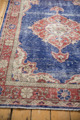 Distressed vintage Oushak rug showing faded cobalt blue field and ivory spandrel detail.