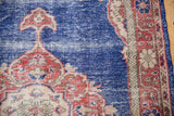 Distressed vintage Oushak rug: textural cobalt blue field with faded rust spandrel.