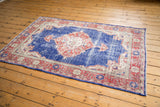 Corner of distressed Oushak rug with cobalt blue field, faded terracotta border, intact selvage.