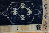 Distressed navy Oushak rug pile showing stepped geometric pattern, beige motifs, and selvage.
