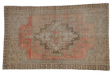 Distressed vintage Oushak rug with stepped medallion, faded rose and beige germinating motifs.