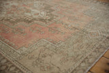 Distressed Oushak rug's rose and beige pile, showcasing wear to knot heads.