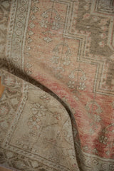 Distressed vintage Oushak rug showcasing low pile, faint foundation, and time-softened rose and beige tones.