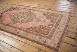 Distressed vintage Oushak rug's blush field, brown floral palmettes, and geometric borders.