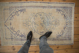 Distressed texture of vintage Oushak rug's faded blue diamond and wave borders.