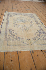 Distressed vintage Oushak rug, showing wear to knot heads and faded blue floral motifs.