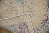 Vintage distressed Oushak rug pile, with worn ivory and faded blue patterns, revealing folded selvage.