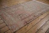 Vintage distressed Oushak rug with stepped medallion, dusty rose, and worn foundation.