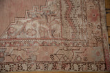 Distressed vintage Oushak rug corner, revealing foundation with dusty mauve and ivory stepped pattern.