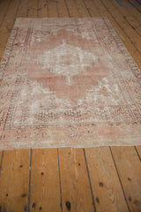 Dusty mauve and ivory serrated motifs on a worn, distressed vintage Oushak rug.