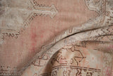 Worn pile of vintage distressed Oushak rug with visible foundation, dusty mauve, serrated motifs.