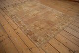Distressed vintage Oushak rug corner, showing muted starburst border and abrashed beige field.