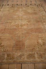 Distressed vintage Oushak rug with faded medallion, abrashed field, and dusty mauve colors.