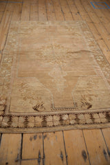 Lower section of distressed Oushak rug, with beige tree-of-life spandrels and dark brown starburst border.