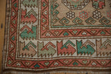Distressed Oushak rug corner: blush, seafoam, oxidized silver geometric motifs, fringe, and selvage.