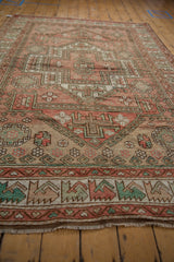 Decorative distressed Oushak carpet with dusty rose, green guls, and wave motif.