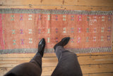 Distressed Oushak runner with dusty blush field, geometric patterns, and worn texture.