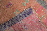Distressed Oushak rug runner detail: dusty blush pile, mint geometric motifs, and pink checkered border.