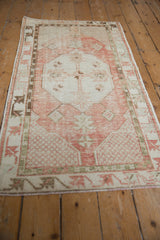 Vintage distressed Oushak rug corner with lattice spandrel and floral border in faded cinnabar and ivory.