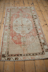 Textured field and faded cinnabar red of the distressed vintage Oushak rug runner.