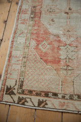 Distressed Oushak runner's intact side selvage, showcasing worn texture and red lattice on beige.