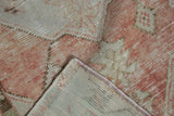 Distressed Oushak rug runner corner showing worn dusty red pile and visible foundation.