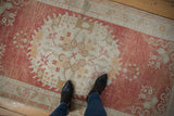 Distressed vintage Oushak rug's abrashed field in cinnabar red, ivory, and beige tones.