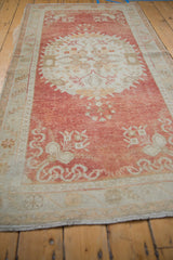 Distressed pile texture with pale cinnabar red abrashed field and ivory floral border.
