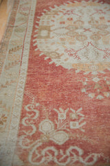 Vintage Distressed Oushak rug section: worn cinnabar red field, ivory border, floral motifs.