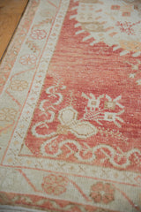 Detail of distressed Oushak rug border and field, showing cinnabar red, ivory, and faint foundation.