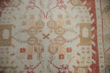 Distressed Oushak rug's muted ivory and cinnabar red geometric motifs.