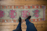 Textural vintage Oushak runner with distressed fuchsia rose bouquets and pale rust starbursts.