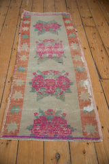 Fuchsia floral bouquet detail on a distressed Oushak rug, showing pale rust starburst border and wear.