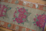 Close-up of distressed Oushak runner: fuchsia rose bouquets, pale rust border, worn pile.