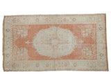 Distressed vintage Oushak rug featuring faded cinnabar red medallion and ivory florals, 3' x 5'7