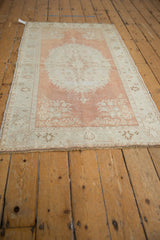 Distressed vintage Oushak rug section with faded cinnabar, ivory floral patterns, and pile wear.