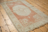 Faded cinnabar and ivory floral motifs on the distressed corner of this vintage Oushak rug.