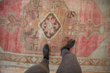 Distressed Oushak runner texture with faded raspberry red and bronze diamond medallion.