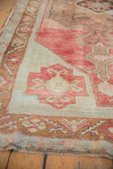 Distressed cherry red pile, patterned bronze border, and fringe of a vintage Oushak rug.